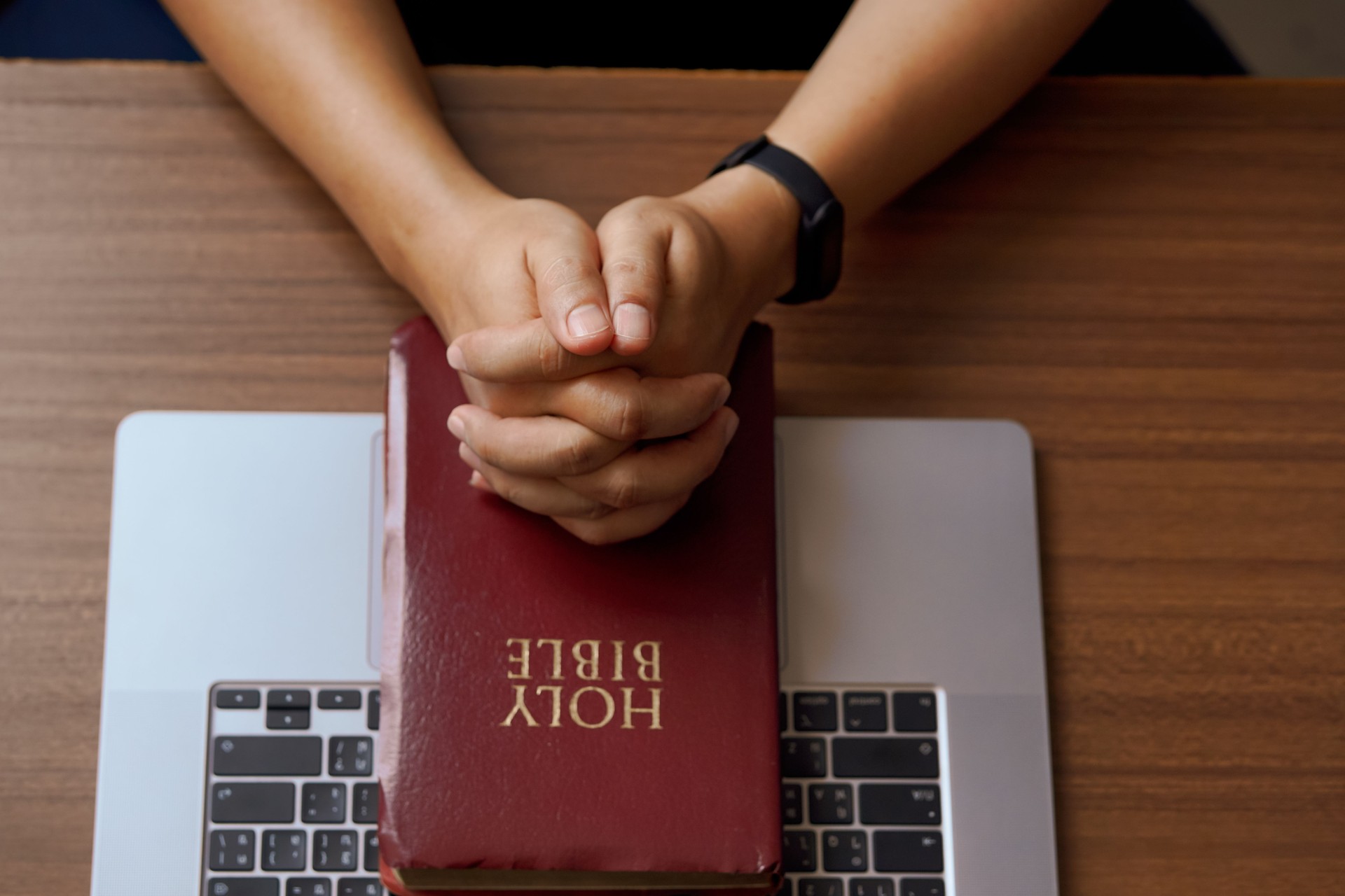 Christian online technology concept. Hands praying of christian with digital computer laptop, Online live church for sunday service. Asian catholic man are reading Holy bible book and online study.